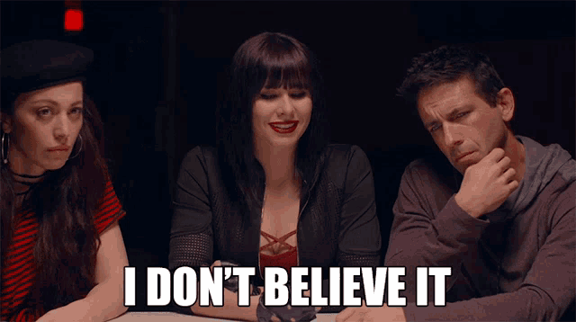 a man and two women sitting at a table with i don 't believe it written on the bottom
