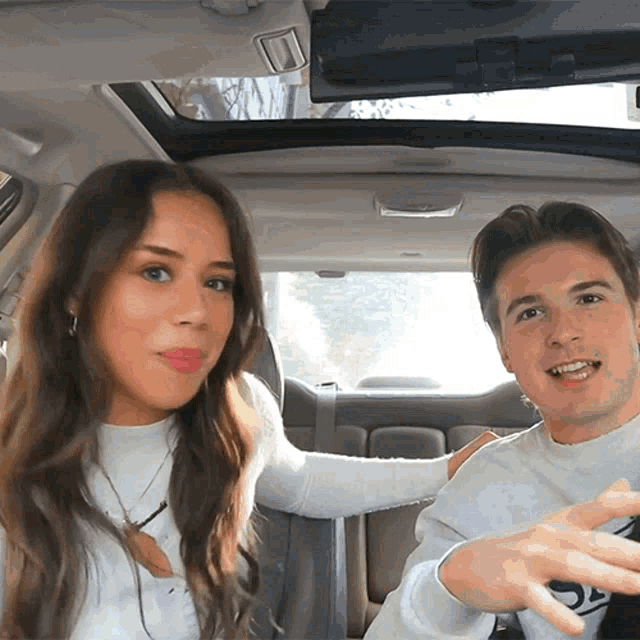 a man and a woman are sitting in a car and the man is wearing a sweater that says s on it