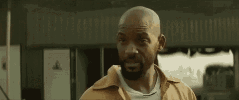 a bald man with a beard and mustache is standing in front of a building and making a funny face .