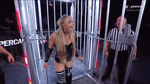 a woman is standing in a cage with a referee standing behind her