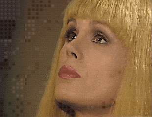 a woman with blonde hair and pink lips looks up