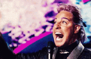 a man in a suit is singing into a microphone with his mouth open
