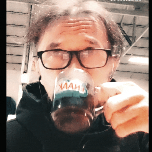 a man wearing glasses is drinking from a mug that says " ham "