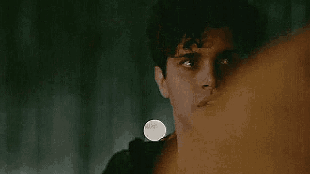 a close up of a man 's face in a dark room with a flashlight in his hand .