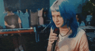 a naked woman with blue hair stands in front of a blue wall
