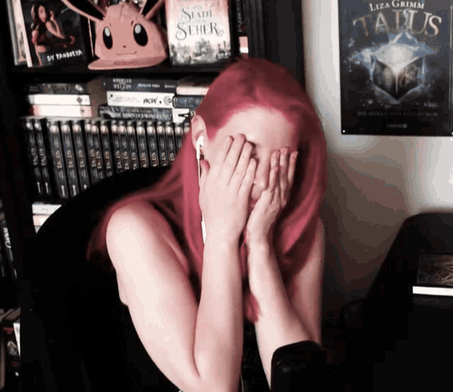 a woman with red hair is covering her face in front of a poster for taurus by luza grimm