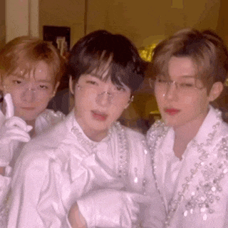 three young men are posing for a picture together while wearing white clothes and glasses .