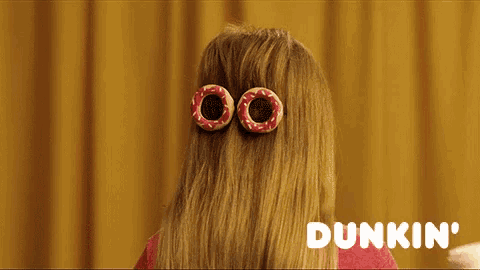 a woman with donuts in her hair holding a cup of dunkin ' coffee