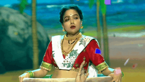 a woman in a red and white crop top is being held by someone 's hand