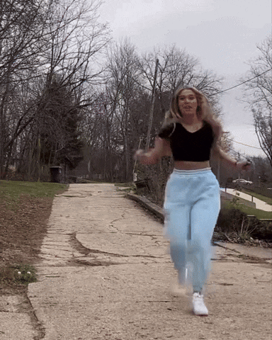 a woman in a black crop top and light blue sweatpants is jumping rope