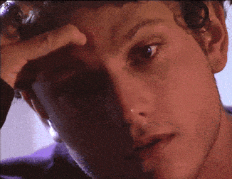 a close up of a person 's face with a hand on their forehead