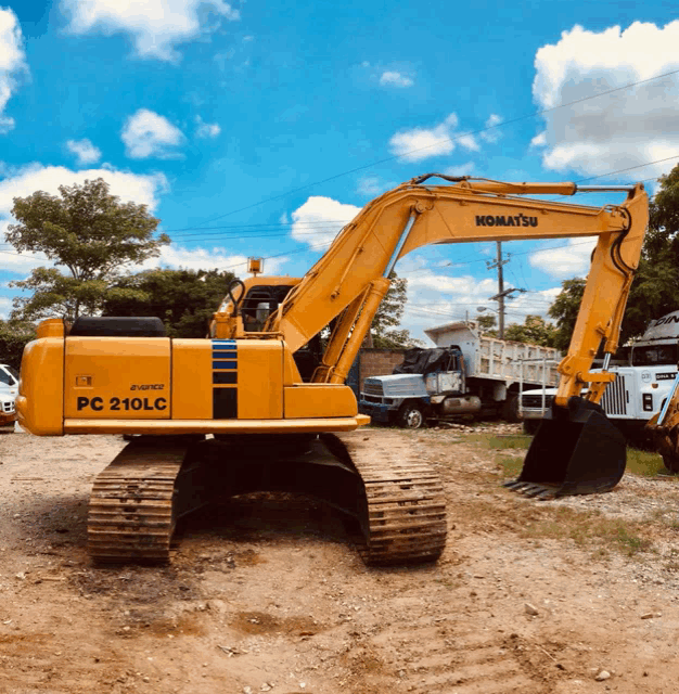 a yellow komatsu excavator sits in a dirt field