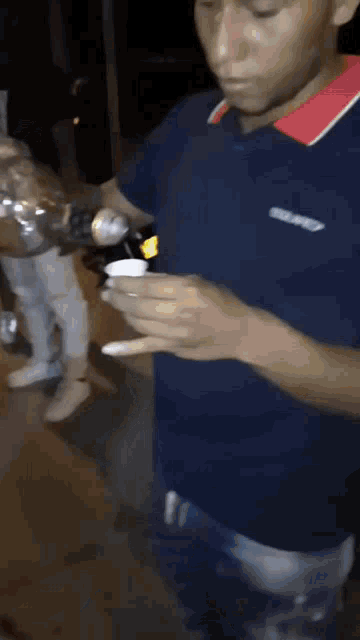 a man in a blue shirt is holding a bottle in his hands