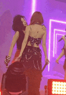 a woman with a tattoo on her back is hugging another woman on stage