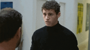 a man in a black turtleneck is looking at another man