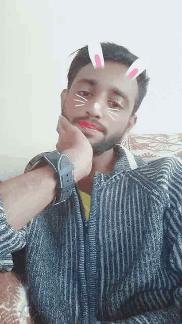 a man with bunny ears on his face is wearing a striped sweater