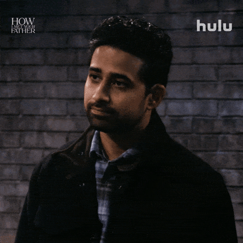 a man stands in front of a brick wall with hulu written on the bottom right