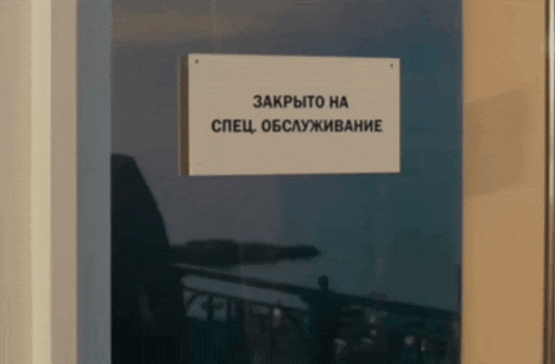 a sign that says " закрыто на спецобслуживание " hangs from a glass door