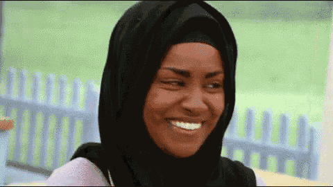 a woman wearing a black hijab is smiling for the camera .