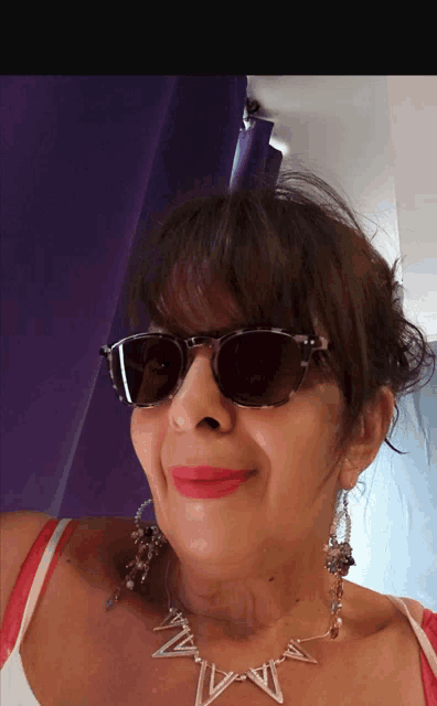 a woman wearing sunglasses and a necklace with the letter w on it