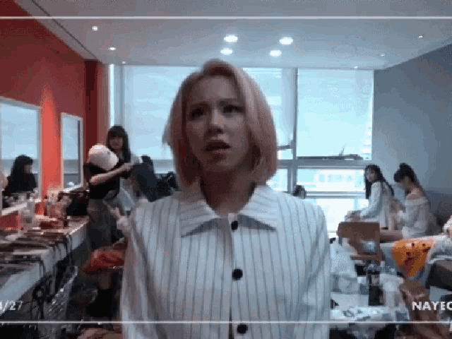 a woman in a striped shirt stands in a room with the date 1/27