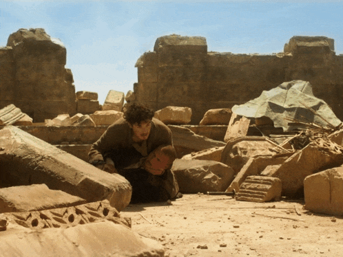 a man is kneeling down in a pile of rocks and rubble