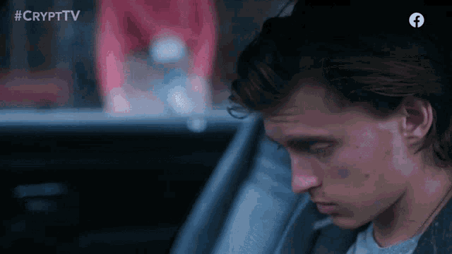 a young man is sitting in a car with the crypttv logo behind him