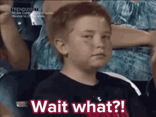a young boy is sitting in a stadium and saying wait what ?