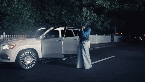 a woman in a long skirt is standing in front of a car