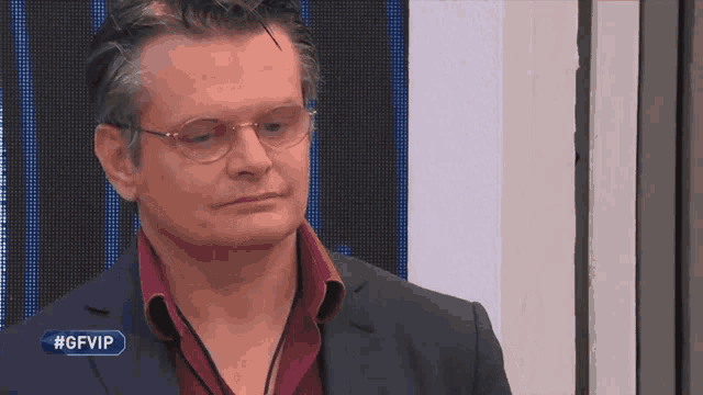 a man wearing glasses stands in front of a screen with #gfvip written on it