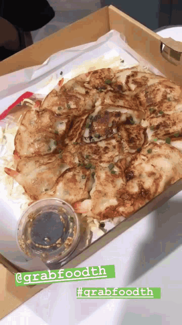 a pizza in a box with a container of dipping sauce