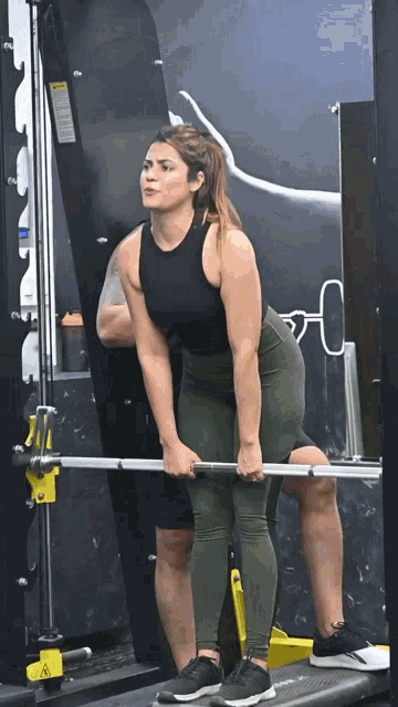 a woman lifts a barbell in a gym