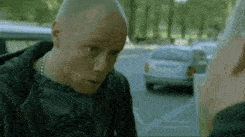 a man is talking to another man in a parking lot .