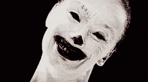 a clown with blood on his face is smiling