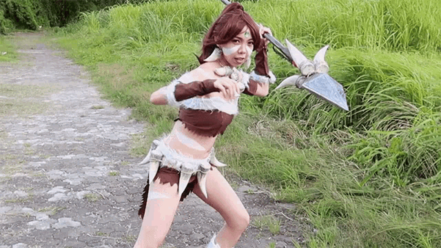 a woman in a costume is holding a spear in her hands .