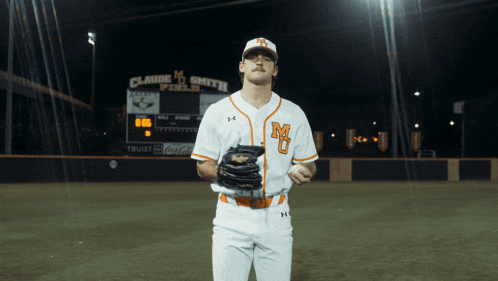 a baseball player stands in front of claude m smith field