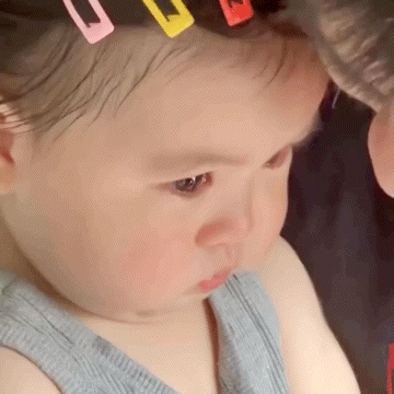 a close up of a baby 's face with hair clips on her head