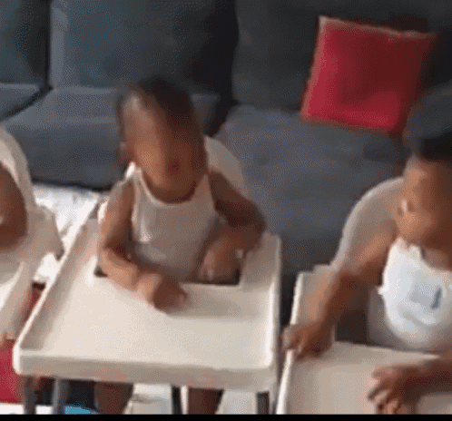 three babies are sitting in white high chairs in a living room .