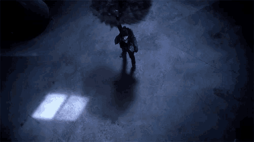 a woman stands in a dark room with a circle in the middle