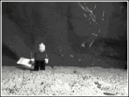 a black and white photo of a lego figure standing in the sand