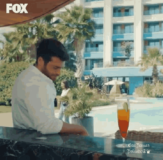 a man is sitting at a bar with a glass of orange juice in front of a hotel .