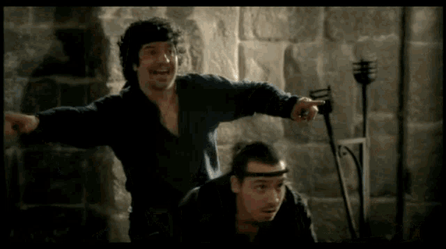 a man in a black shirt is pointing at another man in a black shirt