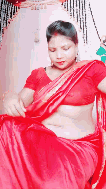 a woman is wearing a red saree and a red shirt .