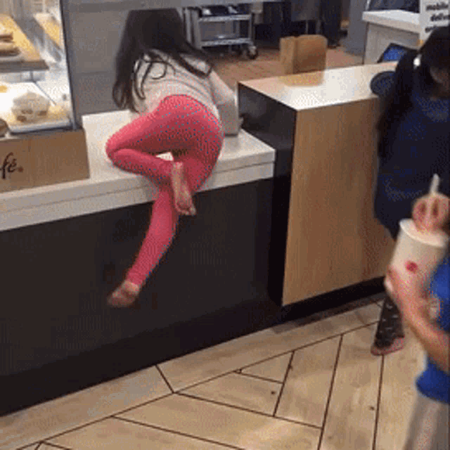 a little girl is sitting on a counter in front of a sign that says ' fe '