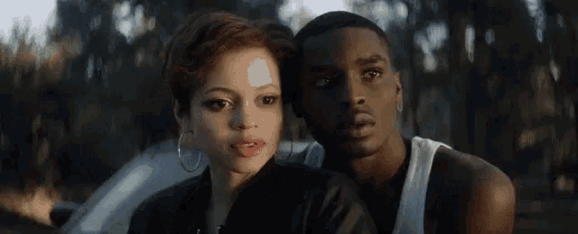 a man and a woman are standing next to each other and looking at the camera .