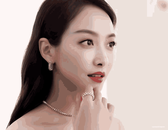 a close up of a woman wearing earrings and a ring with a white background