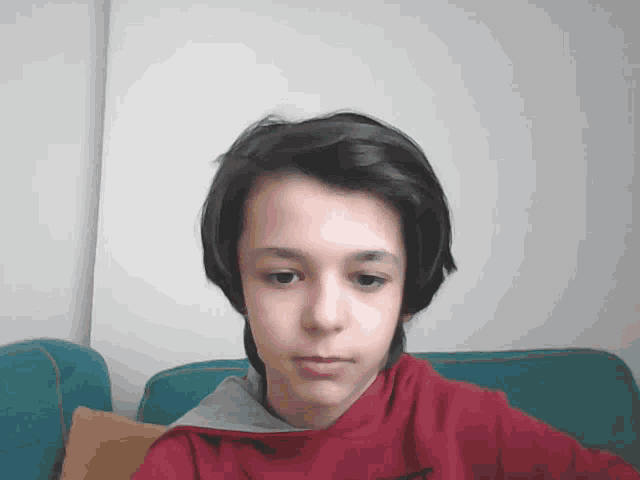 a young boy wearing a red sweatshirt with a grey hood