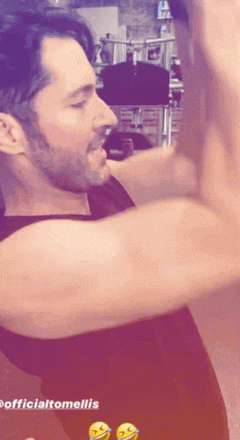a man with a beard is standing in front of a sign that says officialtomellis