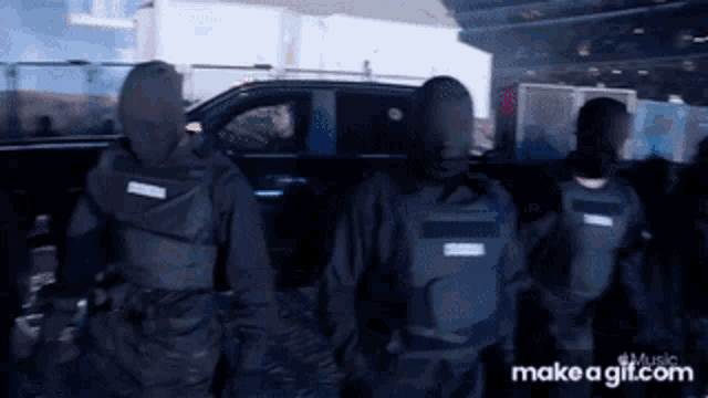 a group of people wearing masks are standing in front of a car with make a gif.com written on the bottom