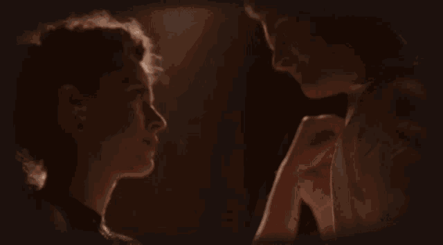 a man and a woman are kissing in a dark room .